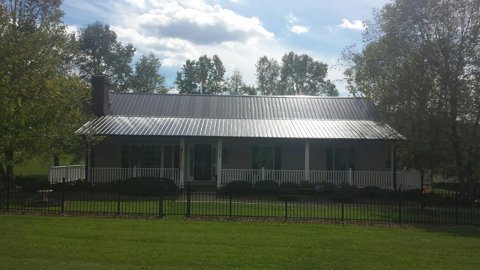 Gray metal roof on a brick ranch with a full width front porch — Gutter Guard Installation work by our crew in Joplin