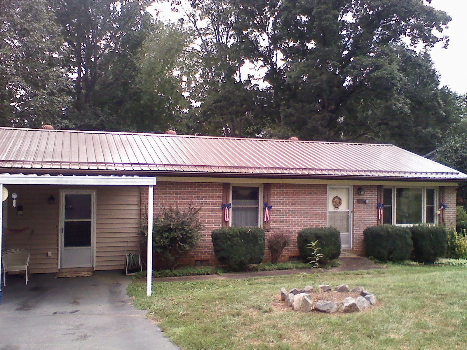 Bronze metal roof and carport on a brick ranch home — Roof Repair work by our crew in Joplin